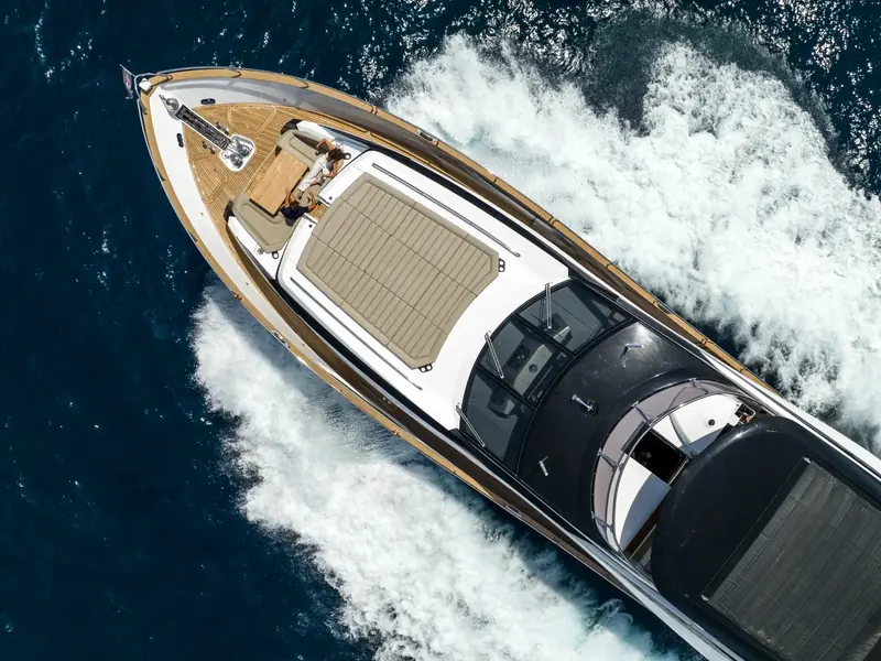 Aerial top-down view of BLUE INFINITY ONE cruising at speed, showing the foredeck, sunpads, and white water wake.